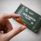 Oud Parfum Pod capsule held between fingers